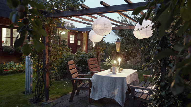 A pergola with a table underneath set for dinner