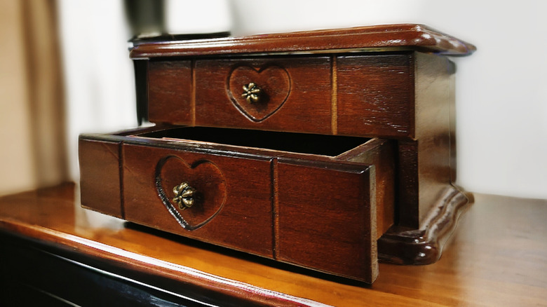 Jewelry box with hearts rests on a table, and one drawer is open