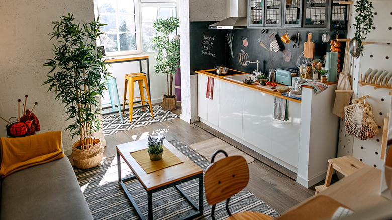 A small studio apartment features a tiny kitchen countertop with a painted blackboard backsplash