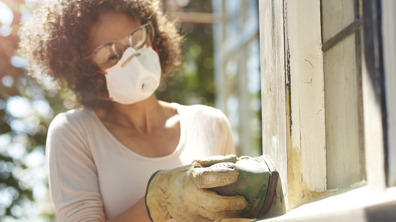 Woman sanding wooden window frame