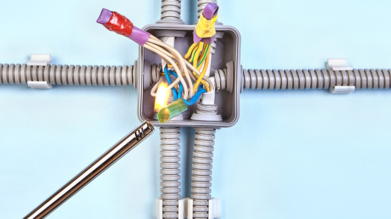 Electrician heating shrink tube onto wiring in plastic junction box