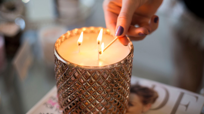 Woman lighting triple wick candle