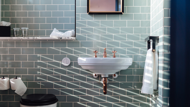 The sink is front and center in a bathroom decorated with stacked teal bricks.