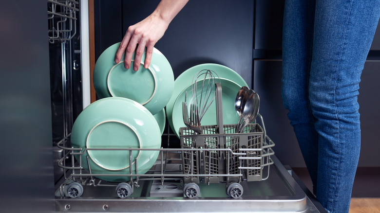 Woman's hand reaching in dishwasher