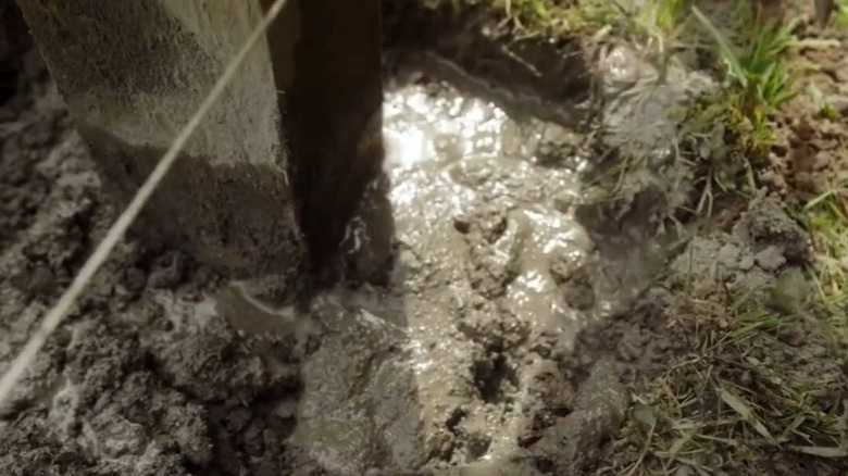 Close-up of freshly poured concrete securing a post in place