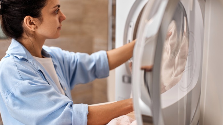 Woman putting towels in washing machine