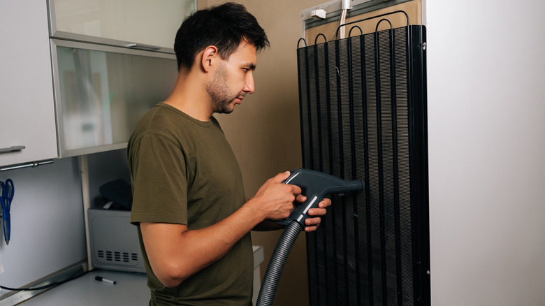 Homeowner carefully cleaning refrigerator coils