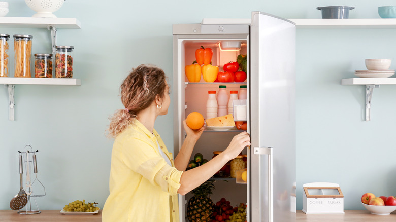 woman picking fruit from fridge