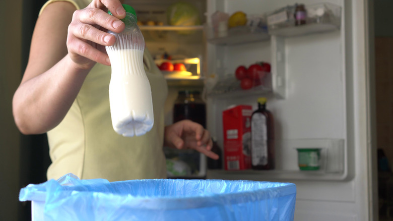 Person tossing milk in trash