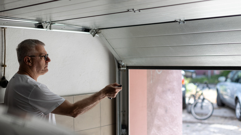 A man opening a garage door with a remote control