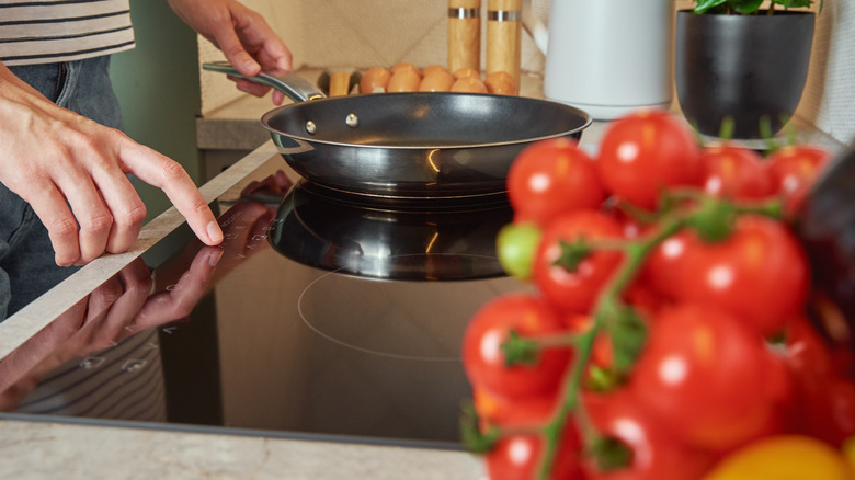 Person using control panel on glass induction cooktop