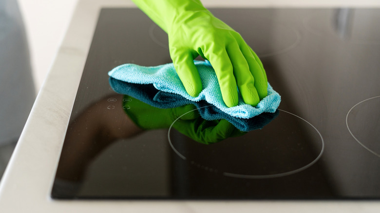 Person cleaning an induction stovetop with a cloth
