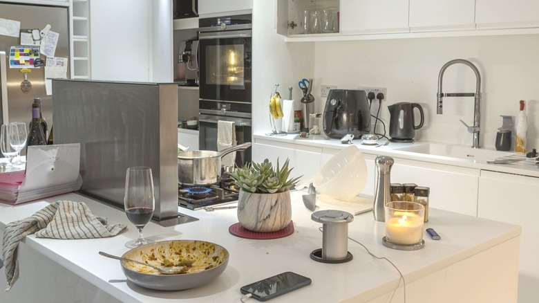 Messy kitchen with items all over the large, wide island countertop.