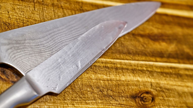 two wet knives on wooden board