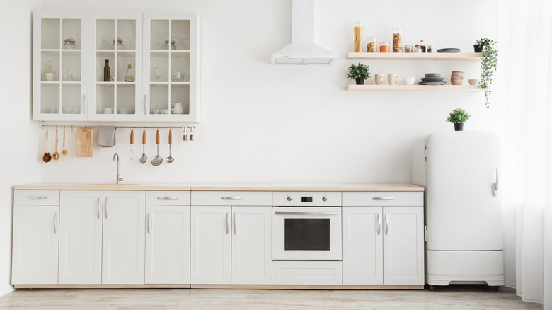 A white kitchen with white cabinets and a refrigerator with produce