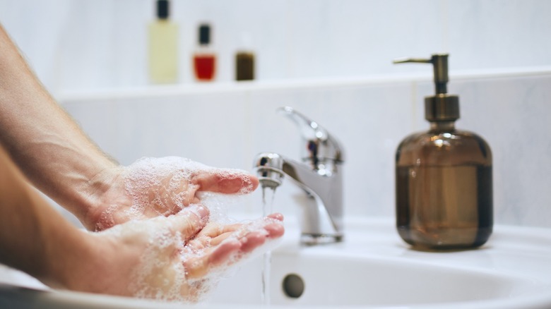 person washing hands liquid soap