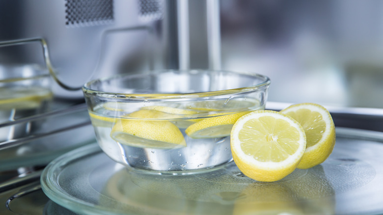 A glass bowl of water and lemon slices inside a microwave
