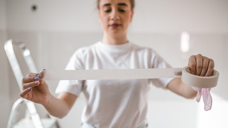 A person unrolling painter's tape