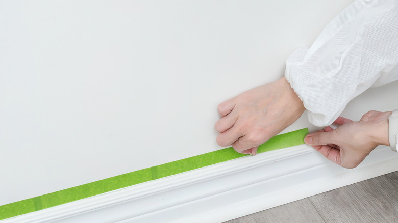 Hands applying painter's tape to a wall
