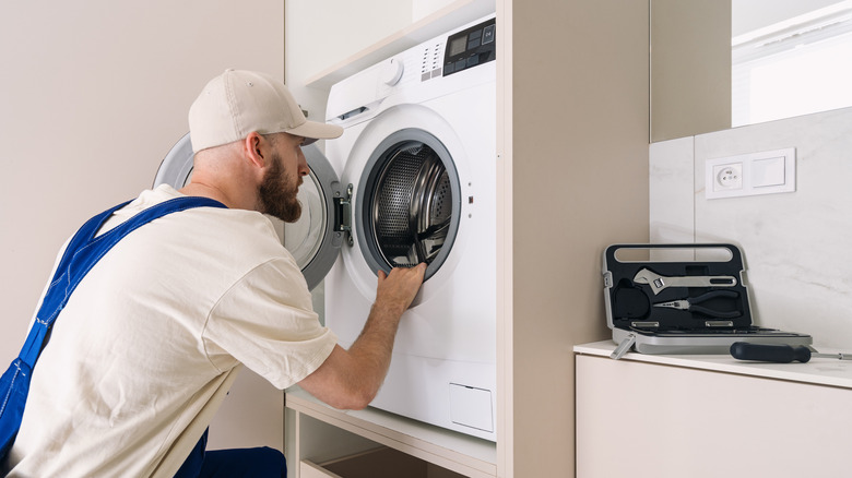 A service technician examines a front-load washing machine