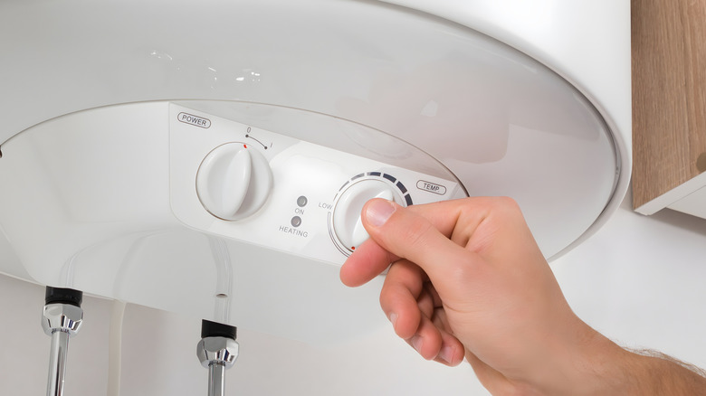 Person turning a switch on a water heater