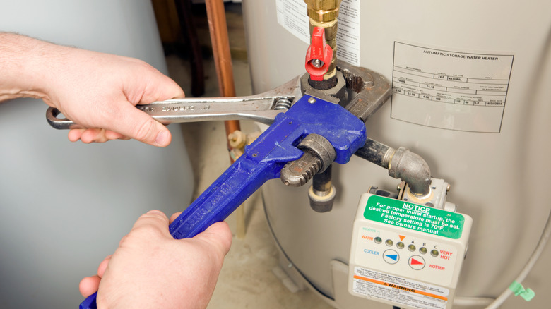 Person adjusting fittings on a gas water heater