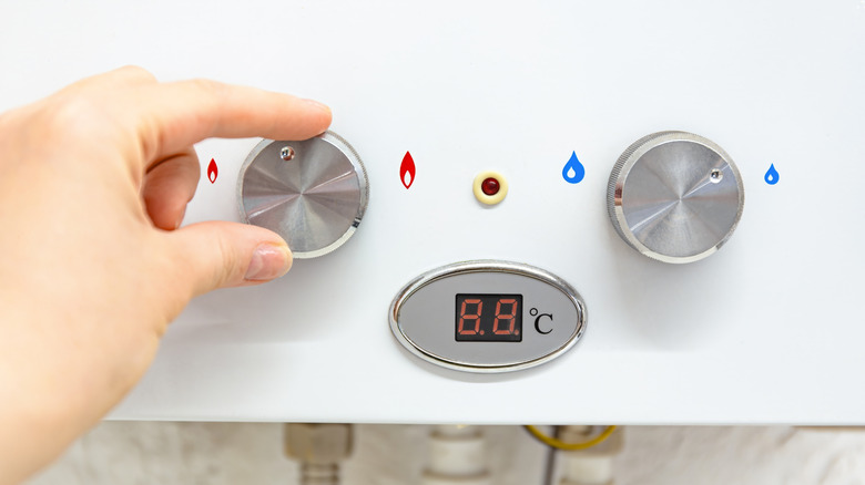 Person adjusting temperature on a water heater
