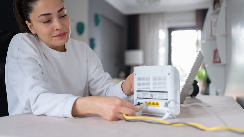 Woman plugging a cord into her WiFi router