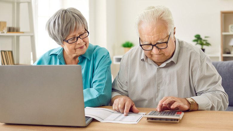Senior couple tabulating expenses together at the dining table