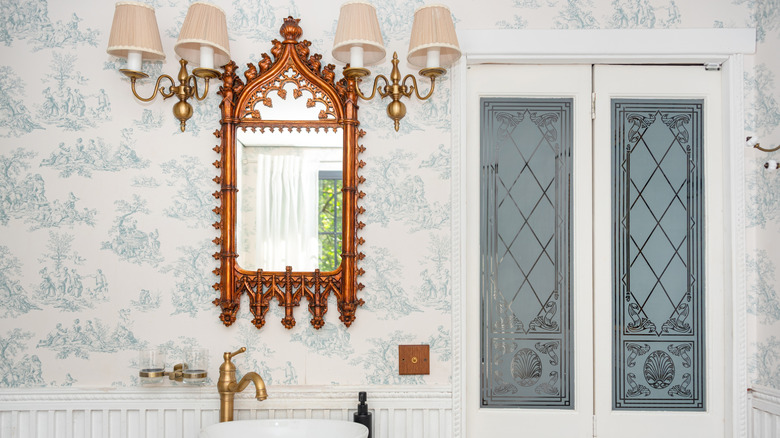 Stylish bathroom vanity with antique mirror, glass panels, and vintage lamps