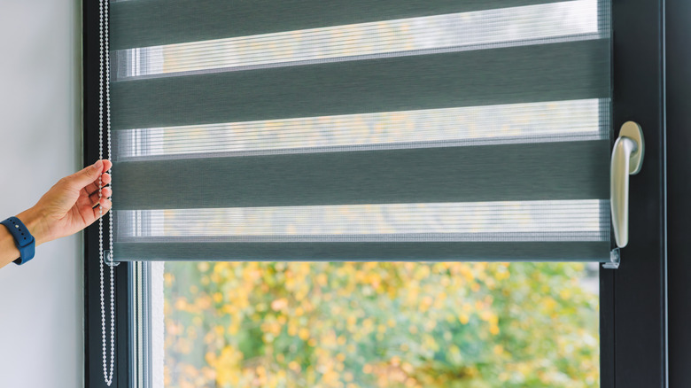 Close up of person pulling window blind cord