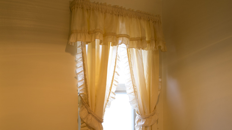 Light yellow frilly curtains.