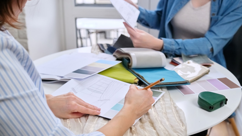 Two designers working on curtain designs at a table.