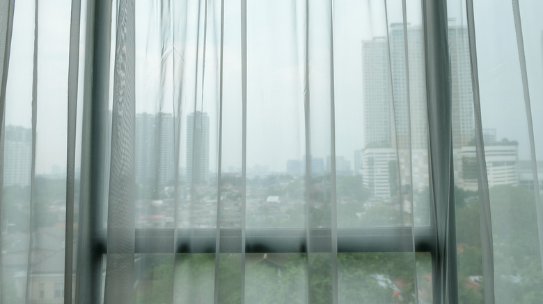 Sheer curtains in front of a window with a city view.