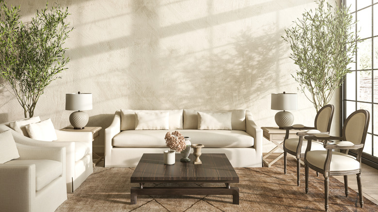 Modern sunny room with large windows, sofa, and side chairs.