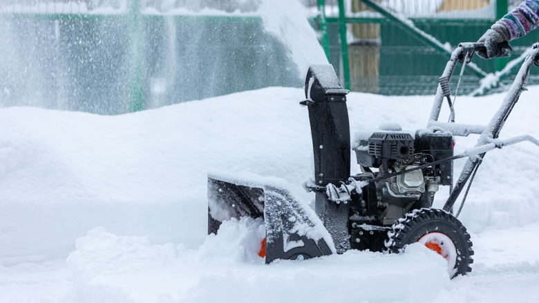 Person snow blowing driveway in winter