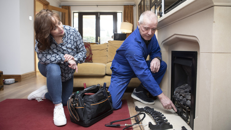 Man inspecting gas fireplace in a living room