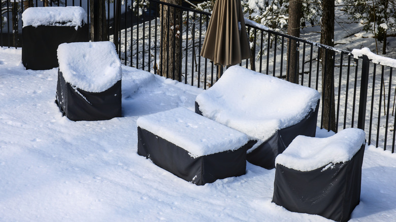 Covered outdoor patio furniture is coated in a thick blanket of snow.