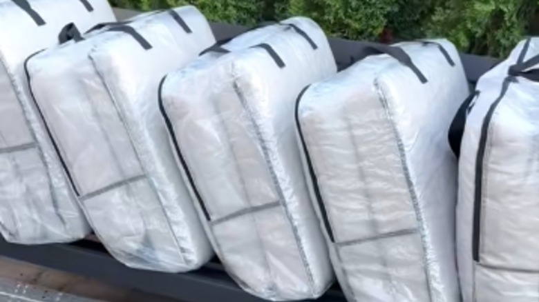 Five IKEA DIMPA storage bags filled with outdoor sofa cushions sit on the empty frame
