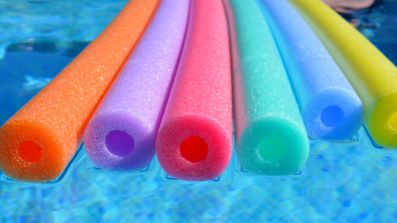Colorful pool noodles floating in pool