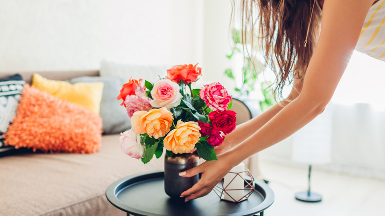 A woman puts a vase on a black side table