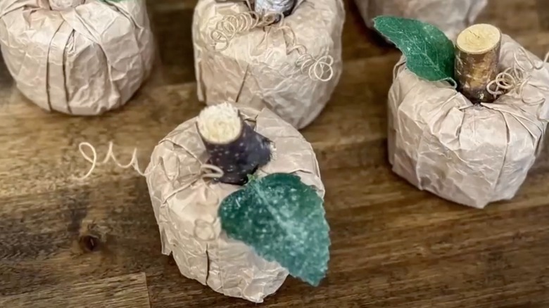 Small rustic pumpkins made out of brown paper bags, pool noodles, and tree branches.