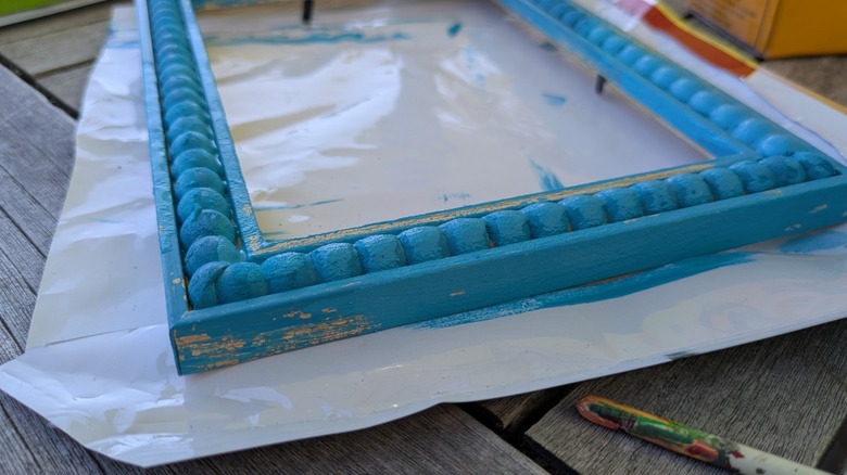 A Dollar Tree wooden picture frame covered in an unattractive coat of turquoise paint