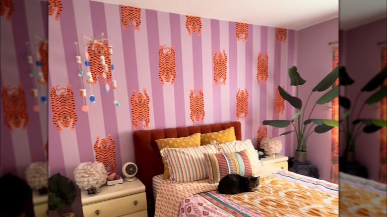 A bedroom with upside-down tiger wallpaper against a pink and white-striped wall