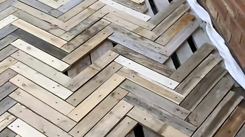 A new deck made of recycled wood pallets, with the slabs arranged in herringbone style.