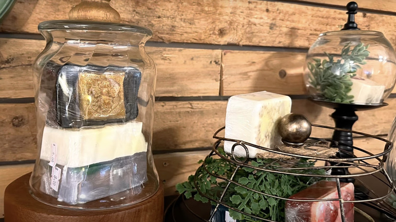 glass cloche with wooden base and soaps underneath