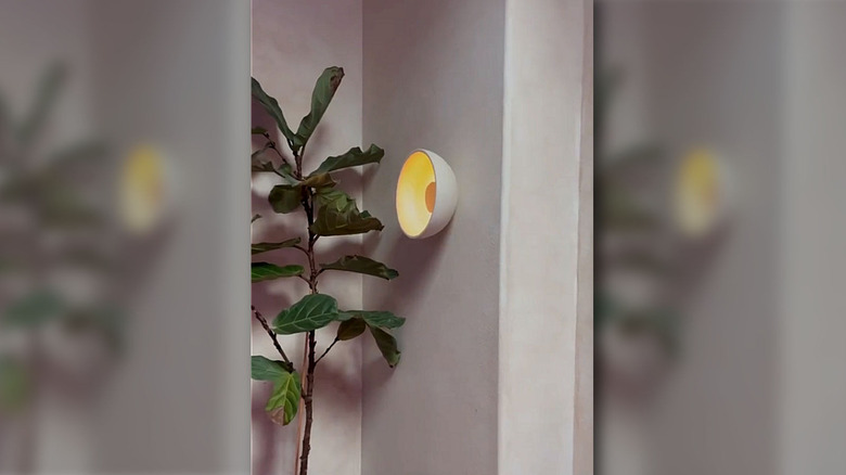 A DIYer assembles a sconce with an IKEA bowl, puck light, spray paint and other supplies