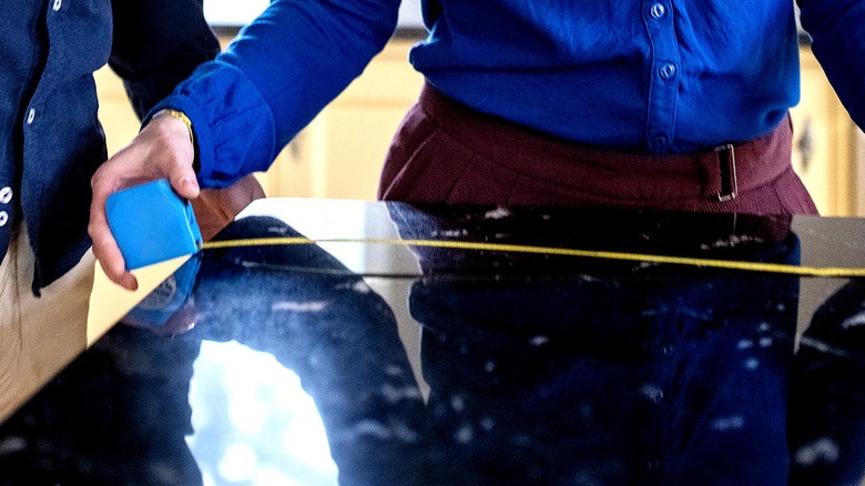 Close-up of a person measuring a granite countertop in a kitchen