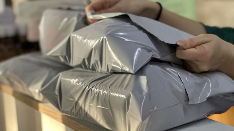 A person sealing a mailer on top of a stack of other mailers