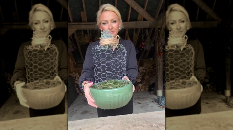 A woman holding a garden cloche made out of chicken wire